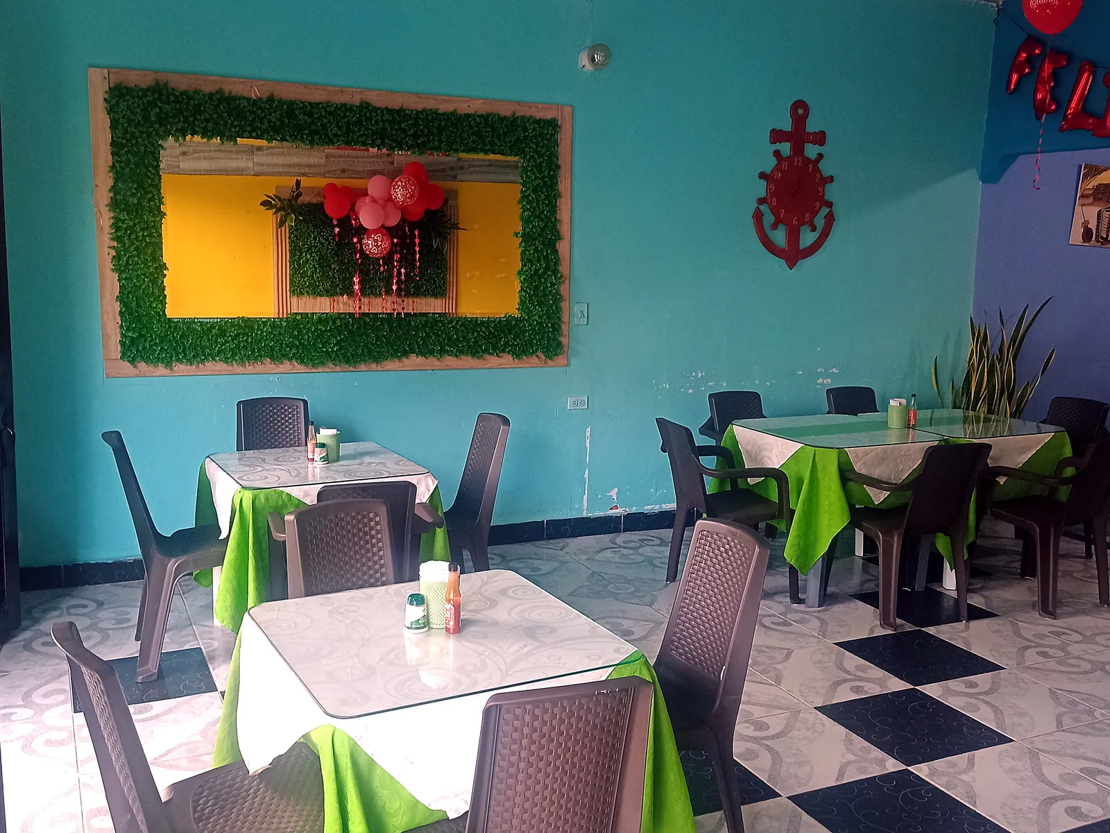 Salón de Sazón Costeño con paredes turquesa y jardín vertical
